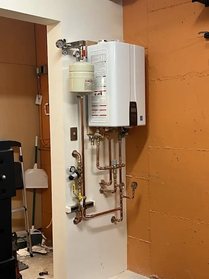 Plumbing technician inspecting water heater connections in North Andover